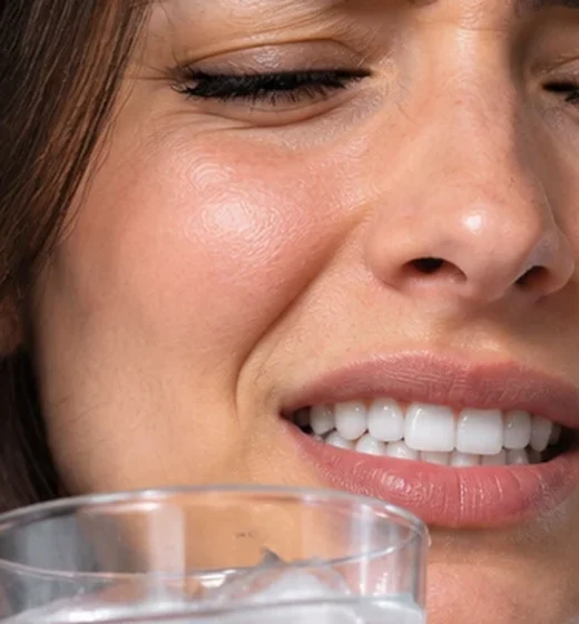 Mujer con punzada en los dientes al tomar agua con hielo